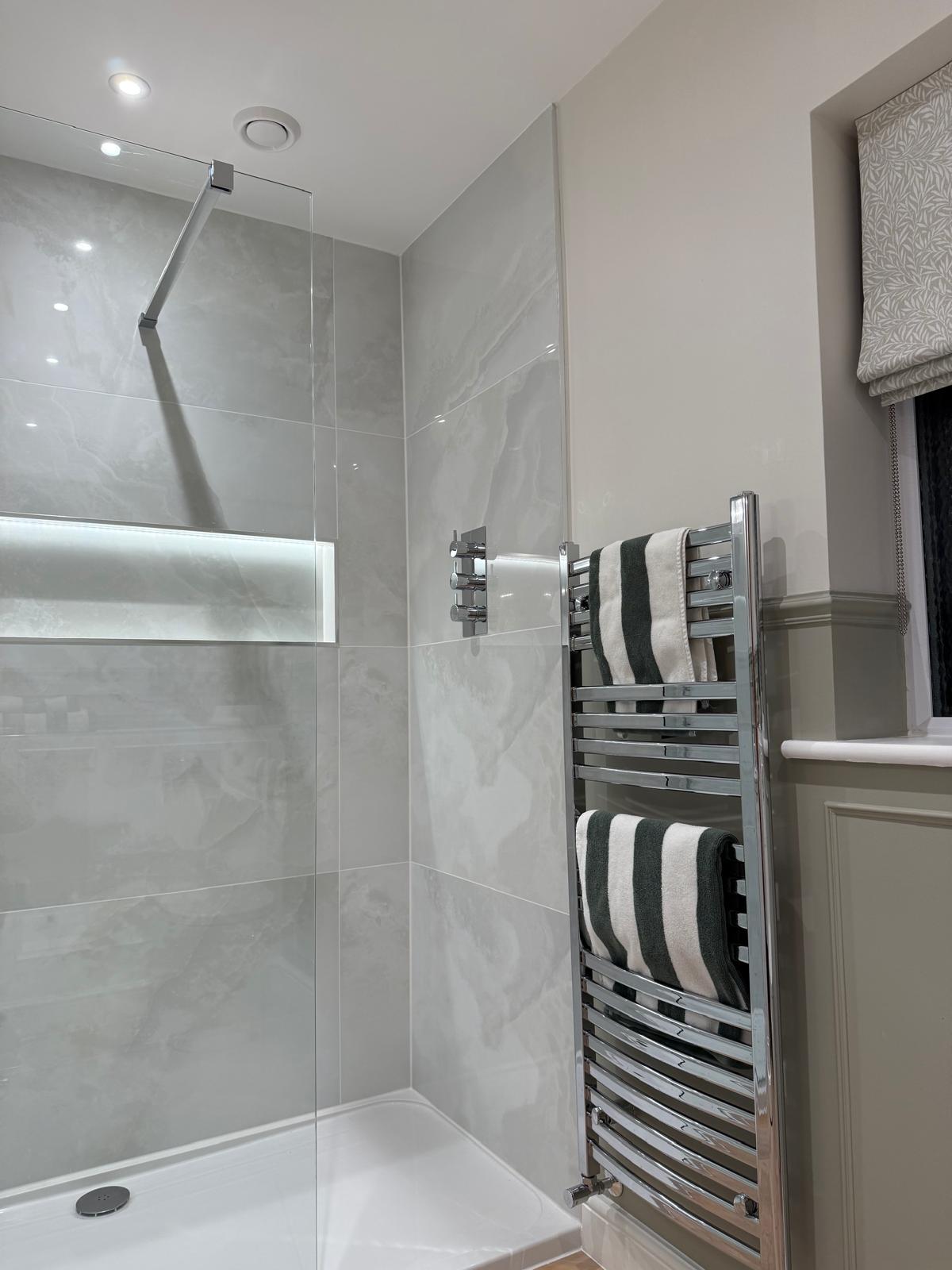 Frameless walk-in shower with chrome towel rail