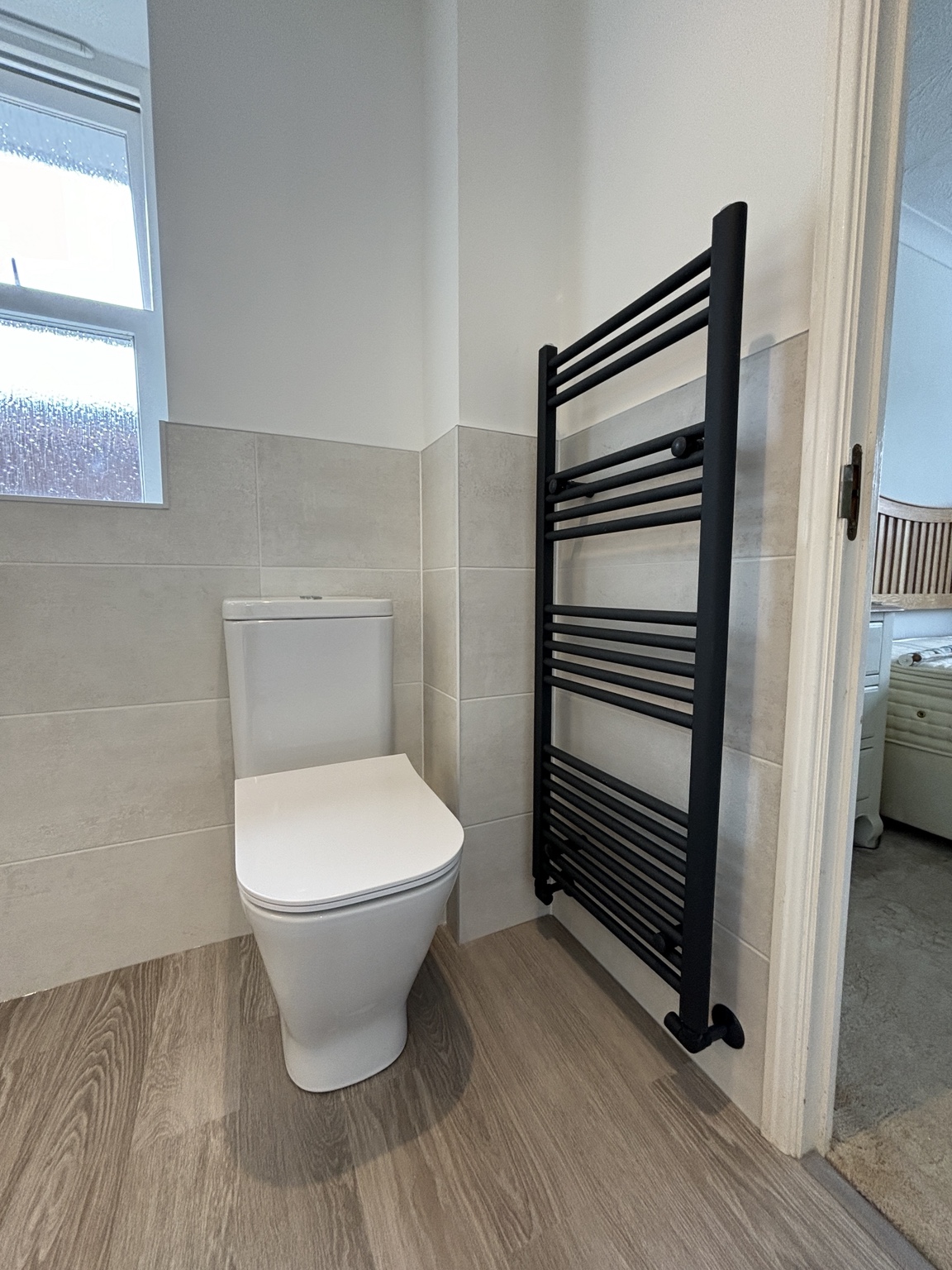 White toilet beside matte black heated towel rail